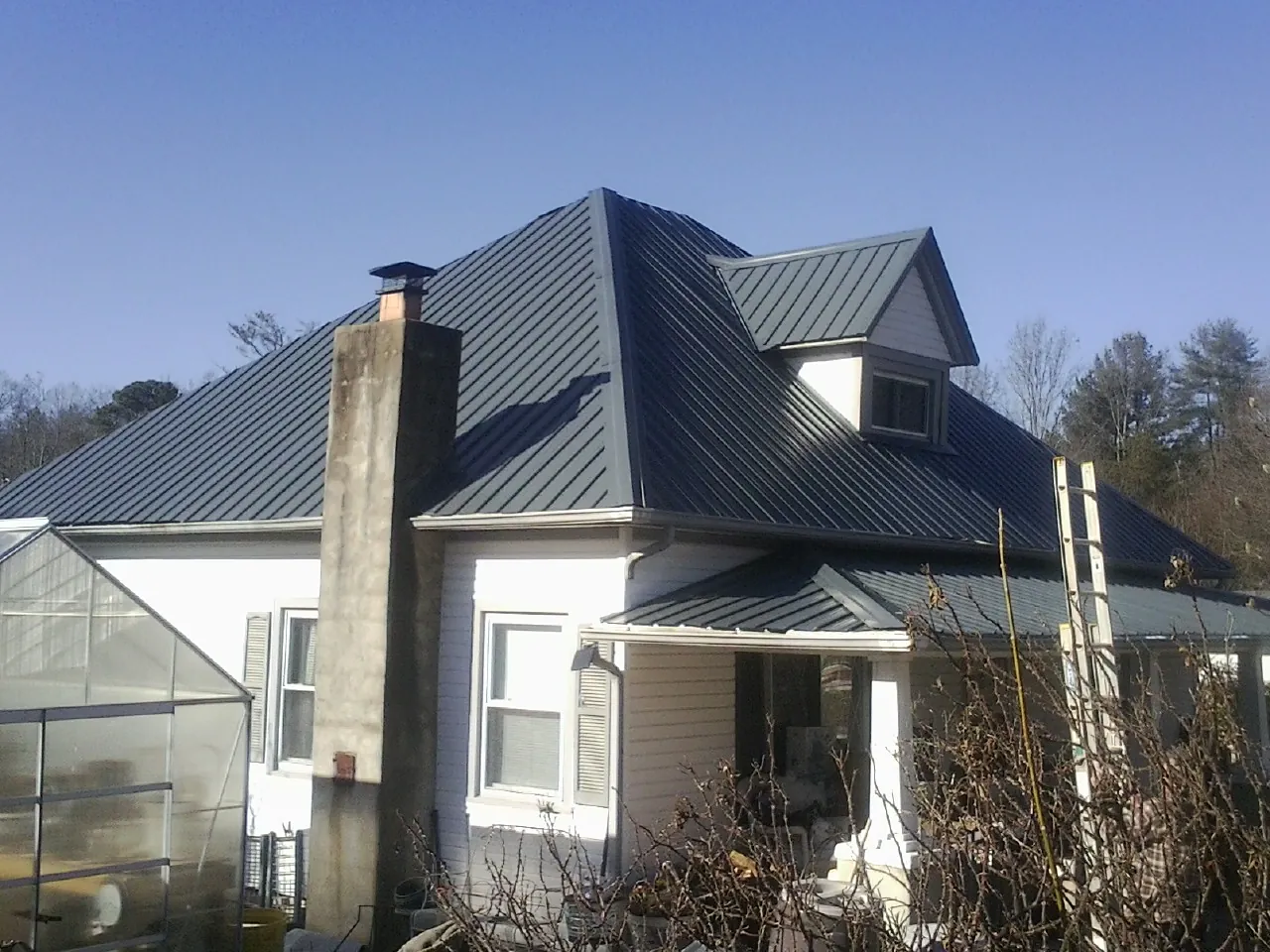 Dark blue standing seam metal roof on a white farmhouse with dormer — Slate & Tile Roof Repair by Roofing Brothers in Waldo