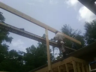 Carpenter setting a ridge beam over a new addition frame — Ice Dam Removal by Roofing Brothers in Waldo