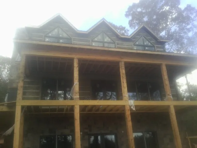 Dormers and porch framing on a large log home under construction — Roof Coating work by our crew in Waldo